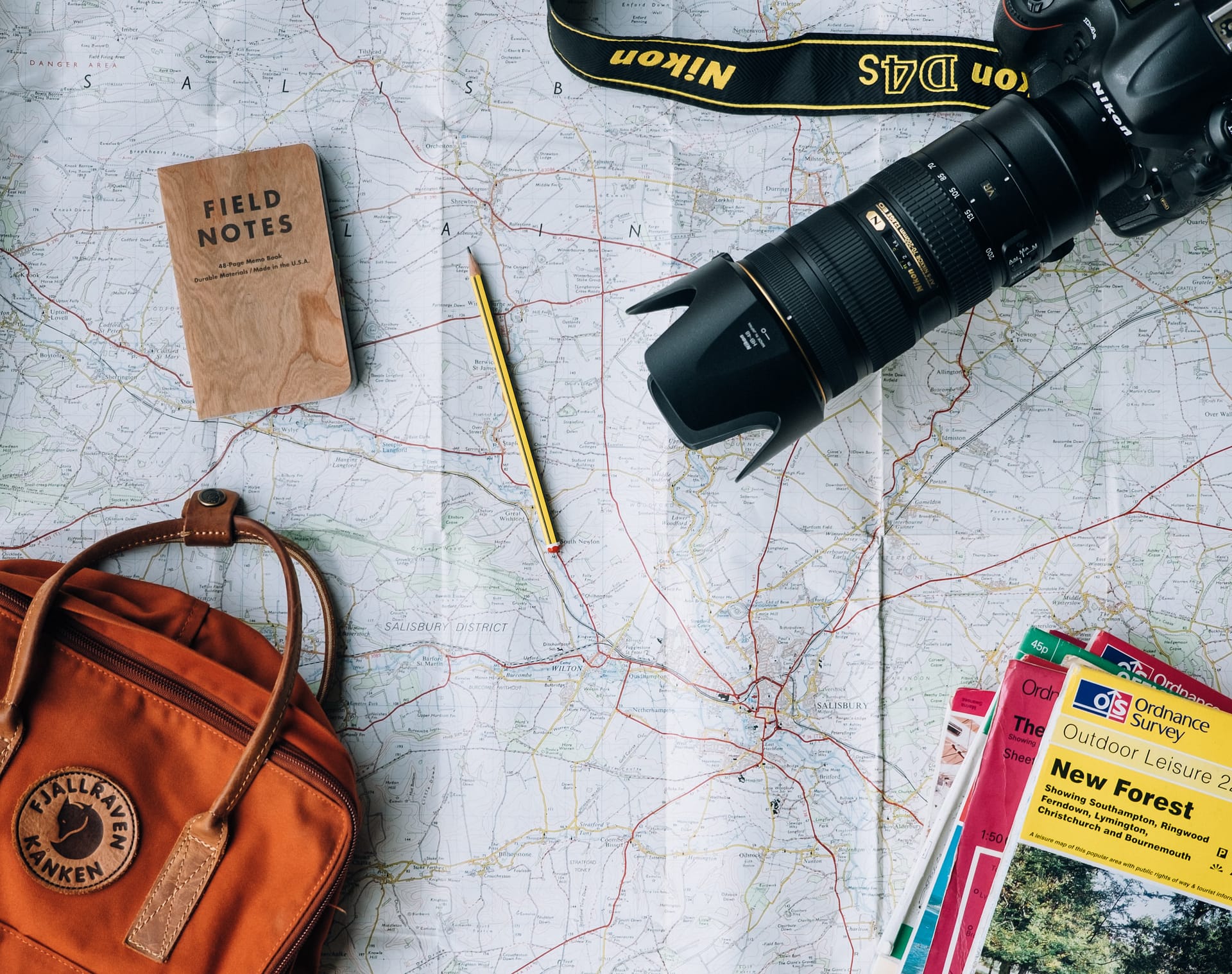 Picture of a map with hiking must haves, like trail maps, a backpack, a camera + field notes notebook